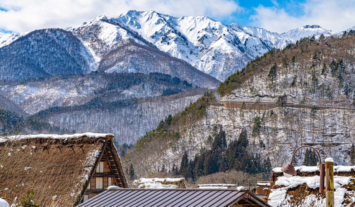 Beautiful landscape of village roofs, pine trees and snow covered mountains in Japan